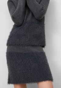 Grijze twee-delige outfit met gestructureerd, fuzzy garen op de rok en het topje. Randdetails op de mouwen, contrasterende gladde secties eronder.