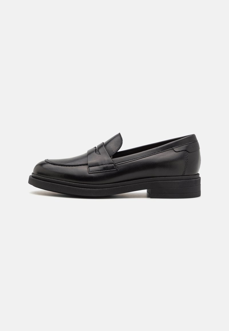 Mocassin pour hommes en cuir noir avec un petit talon empilé, un bout arrondi et un détail de lanière sur le dessus, présenté en profil latéral sur fond blanc.