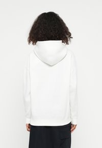 Hvid hættebluse med en afslappet pasform, der har en kengurulomme, ribbede håndled og kant. Glat tekstur, minimalistisk design.
