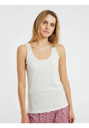 Débardeur beige clair avec un décolleté rond, fines bretelles avec des accents brodés, et une texture lisse et douce. Associé à un bas à imprimé floral.