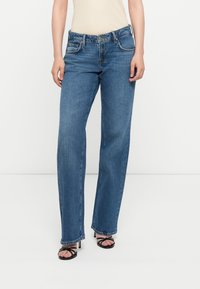 Bredde ben blå jeans laget av denim, med fem lommer, knapp- og glidelås-lukking, og en svakt falmet tekstur.