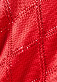 Röd stickad tyg med ett diamantmönster och detaljer av öppet väv. Täta garn ger en mjuk, texturerad yta.