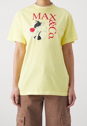 Camiseta de algodón amarilla con mangas cortas, con un gráfico de un personaje de dibujo animado en blanco y negro, y el texto rojo "MAX & Co." en fuente negrita.