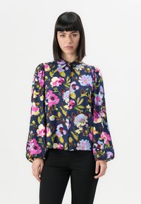 Blomstret bluse med marineblå baggrund og pink og blå blomster, knaplukning og voluminøse ærmer med elastiske manchetter.