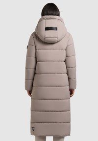 Langer, gepolsterter Mantel in hellem Beige mit Kapuze, horizontal gequilteten Abschnitten, einem Marken-Backpatch und seitlichen Taschen.