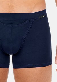 Navy alushortsit, jotka on valmistettu joustavasta kankaasta, sisältävät tukevan etutaskun, mukautuvan vyötärönauhan sekä litteät saumat saumattomaan käyttöön.