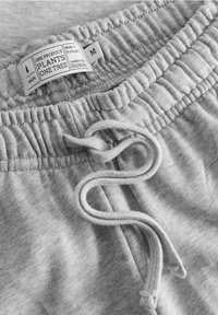 Hellgraue Baumwoll-Sweatpants mit elastischem Bund, Kordelzug und einem Etikett mit der Aufschrift "Hergestellt in Portugal, M." Weiches Material, lässiges Design.
