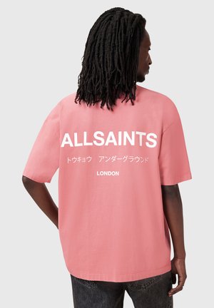 Roze oversized t-shirt met witte opdruk "ALLSAINTS" en Japanse tekst op de achterkant. Soepele katoenen stof, korte mouwen, ontspannen pasvorm.