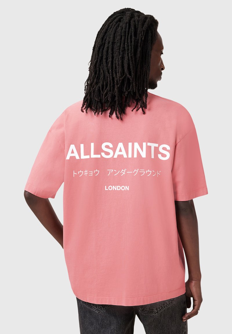 Rózsaszín, oversized póló fehér nyomtatott "ALLSAINTS" szöveggel és japán írással a hátsó részen. Sima pamut anyag, rövid ujjú, laza szabású.