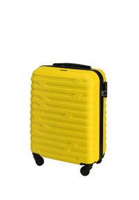 Valigia rigida gialla con design a zigzag testurizzato, cerniere nere, una maniglia superiore e quattro ruote per la mobilità.