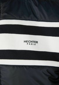 Marineblauw en witte gestreepte sweatshirt met een zachte gebreide textuur en een glad nylon paneel. Toont "HECHTER" en "PARIJS" in zwarte print.