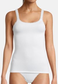 Camisola bianca in cotone con spalline regolabili rifinite in pizzo, caratterizzata da un collo a barca e una vestibilità senza cuciture. Abbinata a slip bianchi con bordi in pizzo.