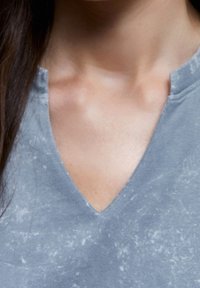Grå v-hals t-shirt med en slidt tekstur, der har et subtilt falmet mønster, blødt stof og et afslappet kravedesign.