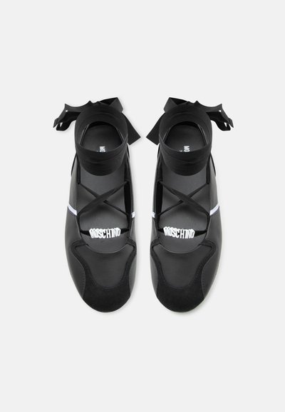 Ballerines noires avec rubans à la cheville et lanières croisées, arborant le logo Moschino blanc sur le bout, vues de dessus.