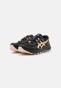 Scarpe da trail running nere con una parte superiore texturizzata, dettagli arancioni, punta rinforzata e suola in gomma robusta.
