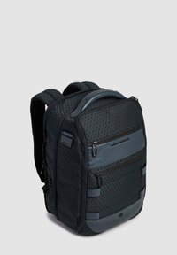 Zaino compatto nero con texture, dotato di più scomparti con cerniera, spallacci imbottiti e una maniglia superiore per il trasporto.