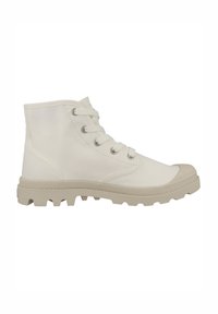 Bottines blanches en toile avec une finition texturée, présentant des lacets ronds, un embout en caoutchouc et une semelle épaisse beige avec des points de traction.