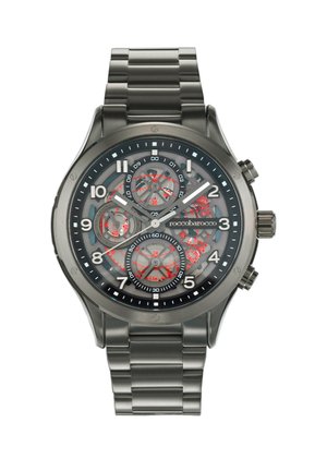 Analoge Armbanduhr mit einem Edelstahlarmband, grauem, rundem Gehäuse, transparentem Zifferblatt, das komplexe Zahnräder zeigt, roten Akzenten und weißen Stundenmarkierungen.
