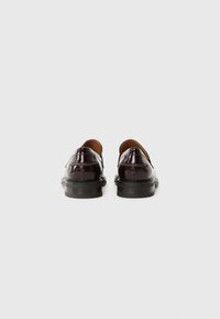 Dunkelburgunderfarbene Lederschuhe mit glänzender Oberfläche, abgerundetem Zehenbereich und flacher schwarzer Gummisohle. Einfache Nahtdetails auf der Rückseite.