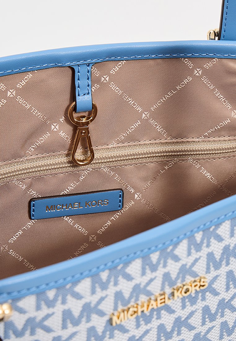 Borsa strutturata con bordo in pelle blu e tela chiara con motivo del logo MK. L'interno include una tasca con zip e l'etichetta del marchio.