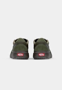 Green suede sneakers with a dark rubber sole, featuring a padded collar and the Vans logo in red on the heel.