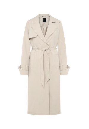 Trench-coat beige clair avec larges revers, taille cintrée par une ceinture, et bracelets aux poignets, doté d'un rabat d'épaule sur le côté droit.