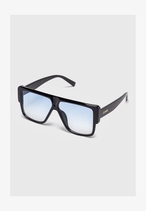 Gafas de sol cuadradas de gran tamaño en color negro con lentes de degradado azul y la palabra "GIANNI" en dorado en la patilla, exhibidas sobre un fondo claro y sencillo.