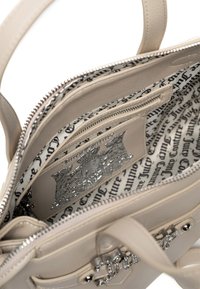 Beżowa skórzana torba na ramię z srebrnymi elementami, z wzorzystym wnętrzem i wieloma przegrodami do organizacji. Zamek błyskawiczny z detalem.