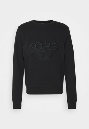 Black long-sleeve sweatshirt with embossed circular "KORS" logo centered on the front, ribbed cuffs and hem.