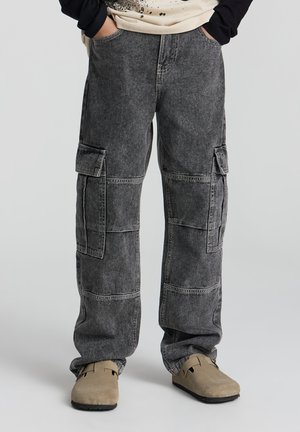 Pantaloni cargo in denim grigio scuro con molteplici tasche e una vestibilità comoda. Il materiale ha una texture morbida e un aspetto leggermente sbiadito.