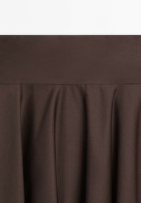 Dark brown pleated fabric skirt or dress close-up showing texture and gathers below a wide waistband.