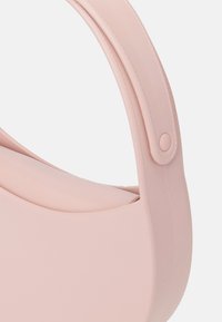 Vaaleanpunainen silikoonipussi, jossa on sileä pinta, pyöreä muoto ja joustava kahva, jossa on pyöreä nappiyksityiskohta.