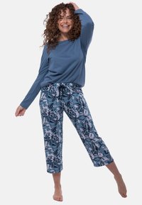 Sininen pitkähihaine paita, joka on yhdistetty kukkakuosisisiin lyhythihaisiin, cropped-pyjama-housuihin, joissa on nauhavyötärö ja pehmeä puuvillamateriaali.