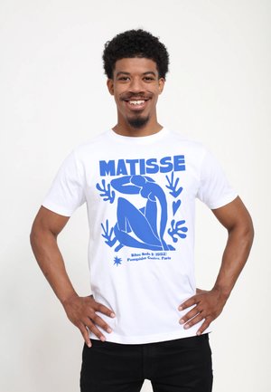 Hvid bomulds T-shirt med iøjnefaldende blå grafisk design af en siddende figur, stiliserede hænder og tekst, der lyder "MATISSE". Korte ærmer, rund hals.