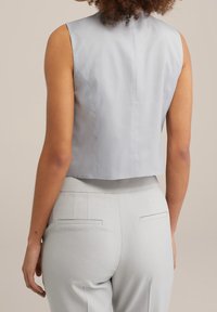 Crop-top utan ärmar i ljusgrå satin med en ren design, med en bred halsringning och subtil detalj på bakseam. Matchad med ljusgrå byxor.