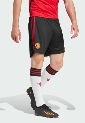 Manchester United Trikot in Rot mit strukturiertem Design, schwarze Shorts mit roten Streifen und weiße Socken mit roten Akzenten und einem Logo.