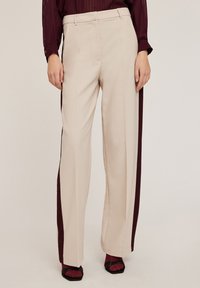 Beige wijde broek met kastanjebruine zijkanten. Gemaakt van gladde stof met een aansluitende tailleband en zonder zichtbare zakken.