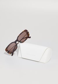 Skilpadde rektangulære solbriller med brune glass, sammen med et hvitt trekantet etui merket "MICHAEL KORS."