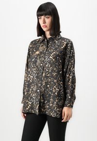 Camicia a maniche lunghe nera e oro con chiusura a bottoni e colletto, caratterizzata da diverse texture e design ispirati agli animali.