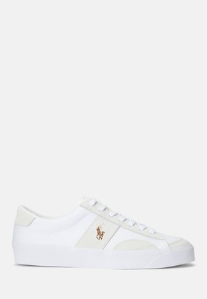 Biały niski sneaker z przednim sznurowaniem, beżowymi akcentami i wyszywanym logo gracza polo z boku.