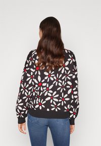 Patterned sweater featuring white flowers with red centers on a black background. Ribbed cuffs and hem, loose fit, with a soft texture.