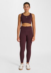 Donkerrood sportbeha- en legging-set vervaardigd uit rekbare stof. De beha heeft een cropped ontwerp; de legging is met hoge taille en naadloze accenten.