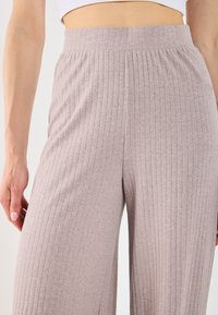 Hellgraue, gerippte, weit geschnittene Hose mit elastischem Bund, die über eine vertikale Textur und einen lässigen Schnitt verfügt. Glattes Material mit einem weichen Aussehen.