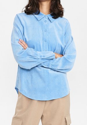 Camicia azzurra in velluto a coste con bottoni, colletto, maniche lunghe e tessitura sottile. Orlo arrotondato con polsini con bottoni.