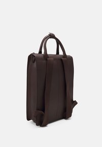 Sac à dos rectangulaire marron foncé avec deux bretelles ajustables et deux poignées arrondies, présenté sur un fond clair uni.