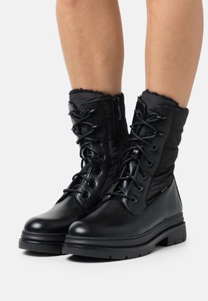 Černé kotníkové boty s lesklou koženou špičkou a polstrovaným nylonovým svrškem, s šněrováním v přední části a bočním zipem pro snadné obutí.
