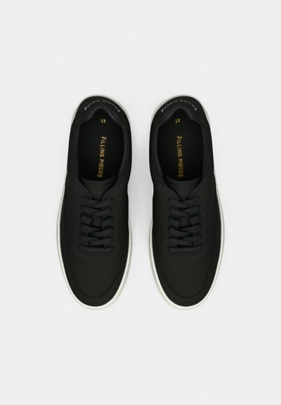 Pair of black lace-up sneakers with white soles, viewed from above, labeled "Filling Pieces" inside.