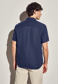 Košile s krátkým rukávem v námořnické modré barvě, se simple límcem a texturovaným povrchem, s kulatým lemem a drapérií látky.