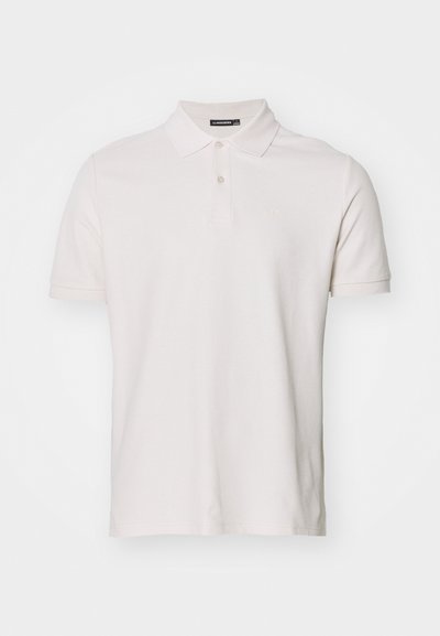 Polo shirt de color beige claro, de mangas cortas, hecho de algodón. Presenta un cierre de botones y un pequeño logo de la marca en el pecho. Textura suave.