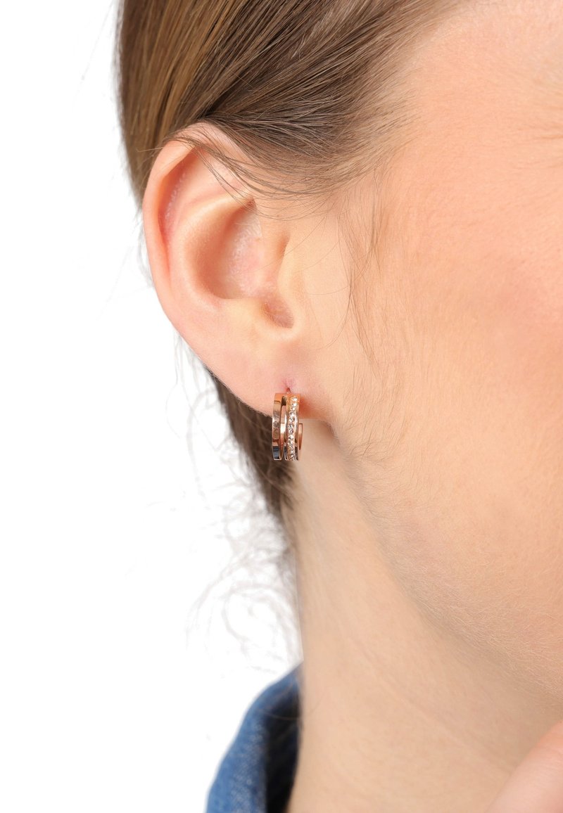 Drie oorringen in gemengde metalen: roségoud, zilver en een sprankelende accent. Ze hebben een gladde, gepolijste afwerking en een ronde vorm.